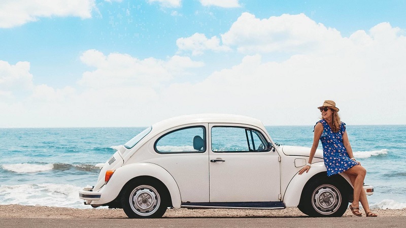 Mulher com carro na beira da praia